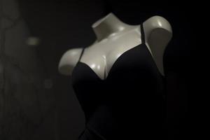 Black clothes in clothing store. White mannequin girl. Showcase details. photo