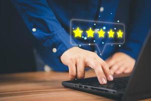 Man using laptop computer to rate service experience in application online. Customer reviews opinion poll satisfaction survey and testimonial. photo