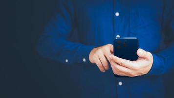 hombre de negocios enviando mensajes de texto por teléfono móvil en su oficina. comunicación, trabajo o reunión, conexión, aplicaciones móviles, tecnología. joven usando un teléfono inteligente en casa. concepto de trabajo de estilo de vida. foto