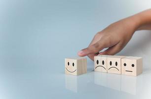 mano eligiendo el icono de la sonrisa feliz. representa la calificación de retroalimentación y la revisión positiva del cliente, el concepto de satisfacción, la encuesta de satisfacción, la evaluación de la salud mental, el día mundial de la salud mental. foto