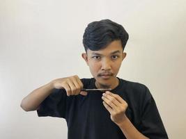 man cutting his own beard using scissors by himself photo