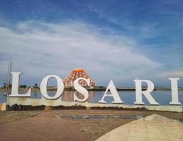 Makassar, Indonesia, October 11, 2022-LOSARI writing as an icon of Losari beach in Makassar city with the background of the appearance of a mosque in the middle of the sea photo