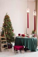 Stylish luxurious interior of the dining room with a Christmas tree. A chair near the round table and a stepladder. Classic modern house photo