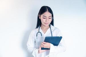 Doctor using tablet computer, close-up of hands at touch pad screen. Patient is at the background photo