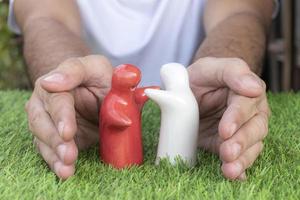 maqueta pareja abrazándose en el suelo de hierba con protector de mano. concepto de día de san valentín foto