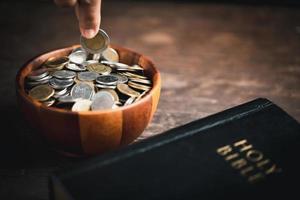 One tenth or tithe is basis on which Bible teaches us to give one tenth of first fruit to God. coins with Holy Bible. Biblical concept of Christian offering, generosity, and giving tithes in church. photo