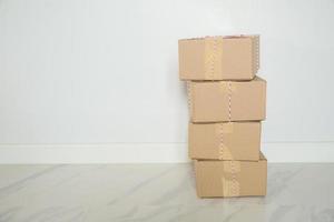 pila de cajas de cartón para mudanzas, habitación vacía con una pared blanca y cajas de cartón con código de barras sin marca en el suelo. entrega de mercancías, compras. cajas de cartón sobre fondo de pared gris. foto