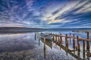 emocionante paisaje en un lago con muelle de madera y barco. foto