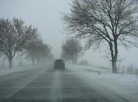 invierno, nieve, ventisca, poca visibilidad en la carretera. coche durante una tormenta de nieve en la carretera foto