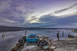 emocionante paisaje de larga exposición en un lago con muelle de madera y barco. foto