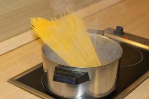 Spaghetti on stove in pan cooking in boiling water with smoke photo