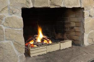 foto de una chimenea de ladrillo al aire libre con un fuego ardiendo en el interior.