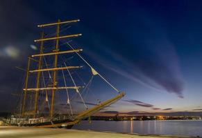 velero en el puerto al atardecer. reflejo de las nubes foto