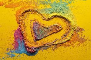 Valentine's Day. Heart-symbol of love, made of multi-colored bright powder, on a yellow background. Copy space. Conceptual. Top view. photo