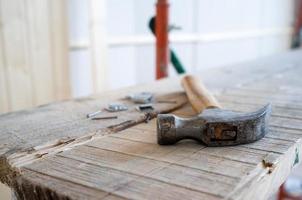 Hammer and nails lie on the scaffolding, against the background of a wall made of wooden slats. Work process. Home renovation. photo