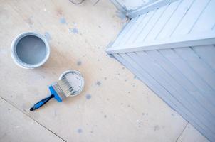 Brush is on the lid next to a metal can containing gray paint. Painting a wooden wall. Home renovation. photo