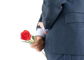 Businessman in suit  holding red roses behind his back photo