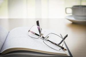 Eyeglasses put on a book with on the desk photo