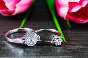 anillos de boda de diamantes con flor de tulipán sobre fondo negro foto