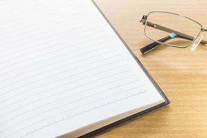 Eyeglasses and open note book with blank page photo