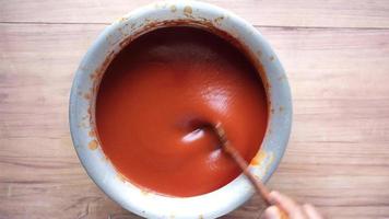 Overhead view of spoon stirring a bowl of thick tomato soup video