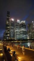 Pedestrians walk on sidewalk with night cityscape in background video