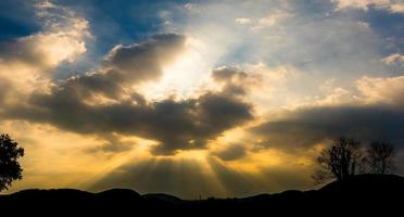 puesta de sol panorámica con nubes en el cielo crepuscular con silueta de montaña foto