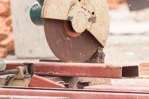 Worker cutting metal with grinder in construction site photo