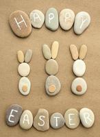 Happy Easter lettering and bunnies from pebbles on craft paper background. Ecological zero waste, eco friendly nature concept. Flatlay, lay out, top view. photo