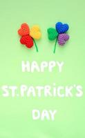 Happy St. Patrick's Day lettering with rainbow lgbt shamrock leaves on green background. Flatly top view concept photo