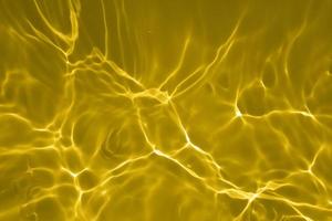 Defocus blurred transparent yellow colored clear calm water surface texture with splashe and bubble. Trendy abstract nature background. Water waves in sunlight with copy space. Yellow watercolor shine photo