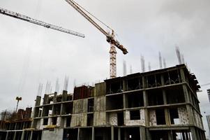 Large powerful construction cargo industrial crane on a construction site of new buildings and houses against the sky photo