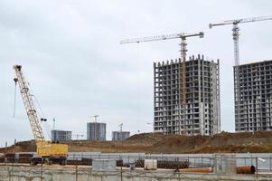 Construction of large modern monolithic frame houses, buildings using industrial construction equipment and large high cranes. Construction of the building in the new micro district of the city photo