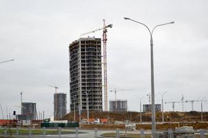 Construction of large modern monolithic frame houses, buildings using industrial construction equipment and large high cranes. Construction of the building in the new micro district of the city photo