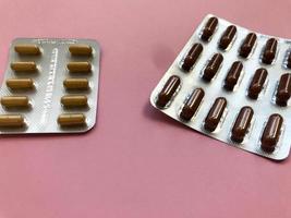 Medical pharmaceutical brown medications for the treatment of diseases and the killing of microbes and viruses tablets and vitamins blisters blisters from coronavirus covid-19 on a pink background photo