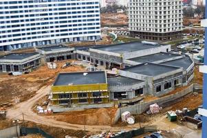 Construction of a one-story comfortable modern new monolithic frame building of a shopping center within walking distance in a new area. View from above photo