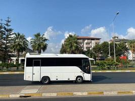 White bus and beautiful modern buildings, architecture, road and palm trees in a warm tropical oriental southern country resort photo