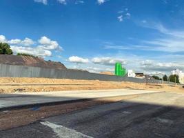 construcción en la ciudad. unidad de hormigón verde para la preparación de material para la fabricación de bloques de construcción. Detrás de una alta valla gris se encuentra un montón de arena y piedras. foto