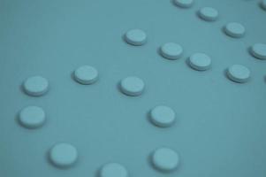 medicamentos farmacéuticos médicos redondos para el tratamiento de enfermedades y la eliminación de microbios y virus píldoras y medicamentos vitamínicos para el coronavirus gris sobre un fondo azul foto
