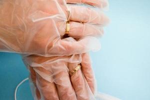 Gold wedding rings on hands in protective medical rubber disposable gloves for protection against dangerous deadly diseases of microbes and viruses by coronavirus covid-19 on a blue background photo