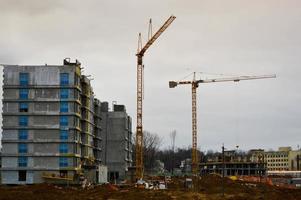 construcción de grandes casas monolíticas modernas, edificios que utilizan equipos de construcción industrial y grandes grúas altas. construcción del edificio en el nuevo micro distrito de la ciudad foto