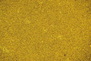 Yellow bright soft rubber flooring safe for sports and workout or on the playground from the many small round pebbles pressed. Background, texture photo