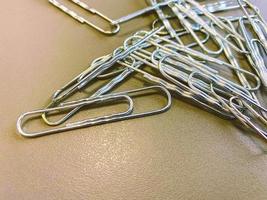 paper clips made of white metal to keep documents together in a normal way. stationery for working with documents in the office on a brown table photo