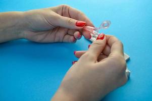 diagnósticos médicos. chica con manicura roja sostiene una lanceta para perforar un dedo. sangre capilar, diagnóstico de su salud para identificar una enfermedad infecciosa foto