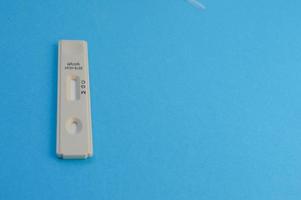 tira de prueba blanca para el diagnóstico de infección por coronavirus. prueba sobre un fondo azul. kit individual para el diagnóstico de la enfermedad. determinación de anticuerpos igg e igm foto