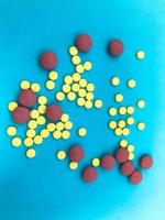 Round multicolored red and yellow medical pharmaceutical medicines for the treatment of diseases killing microbes and viruses pills and vitamins medicines for coronavirus on a blue background photo