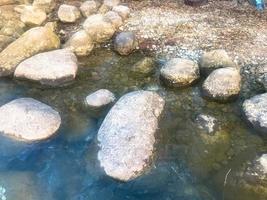 Large round beautiful natural stones cobblestones in water, sea, lake, river. Background, texture photo