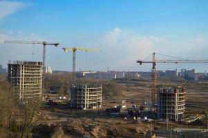 vista superior de un gran sitio de construcción con grúas y edificios que albergan rascacielos monolíticos de hormigón de varios pisos de la gran ciudad de la metrópolis foto