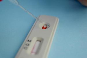 test for coronavirus on a blue background. girl with a bright red manicure makes a blood test. she adds a physical solution to a drop of blood for correct results photo