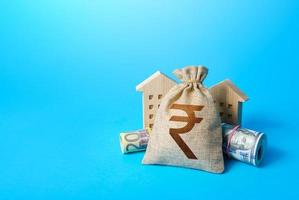 Houses and indian rupee money bag. Asset, financial resource management. Building up capital, saving from inflation risks. Real estate. Savings. Declaration, taxes payment. Bookkeeping and accounting photo